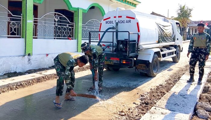 Di Bawah Terik Matahari, Satgas TMMD Bojonegoro Siram Jalan Cor Kesongo
